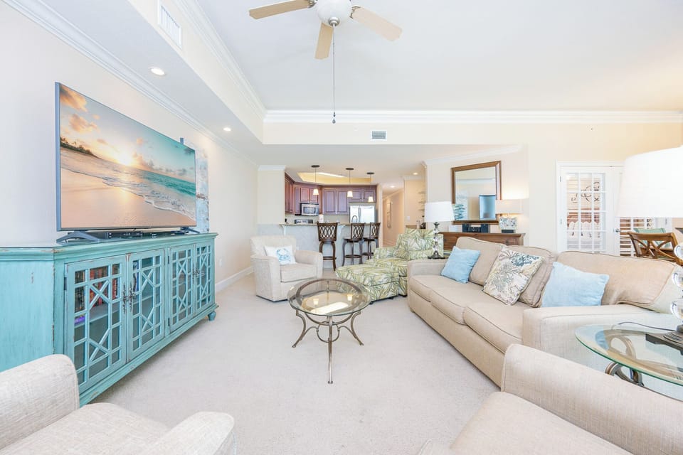 Cozy living room featuring a large TV, comfy seating, and a stylish turquoise cabinet for a welcoming atmosphere