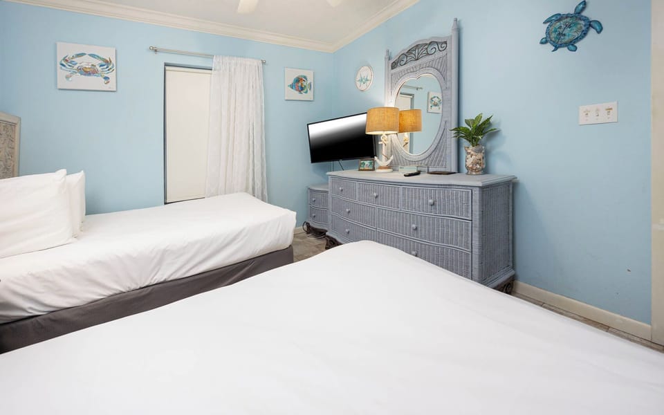 Cheerful guest bedroom with two comfortable double beds, a TV, and bright decor that invites relaxation