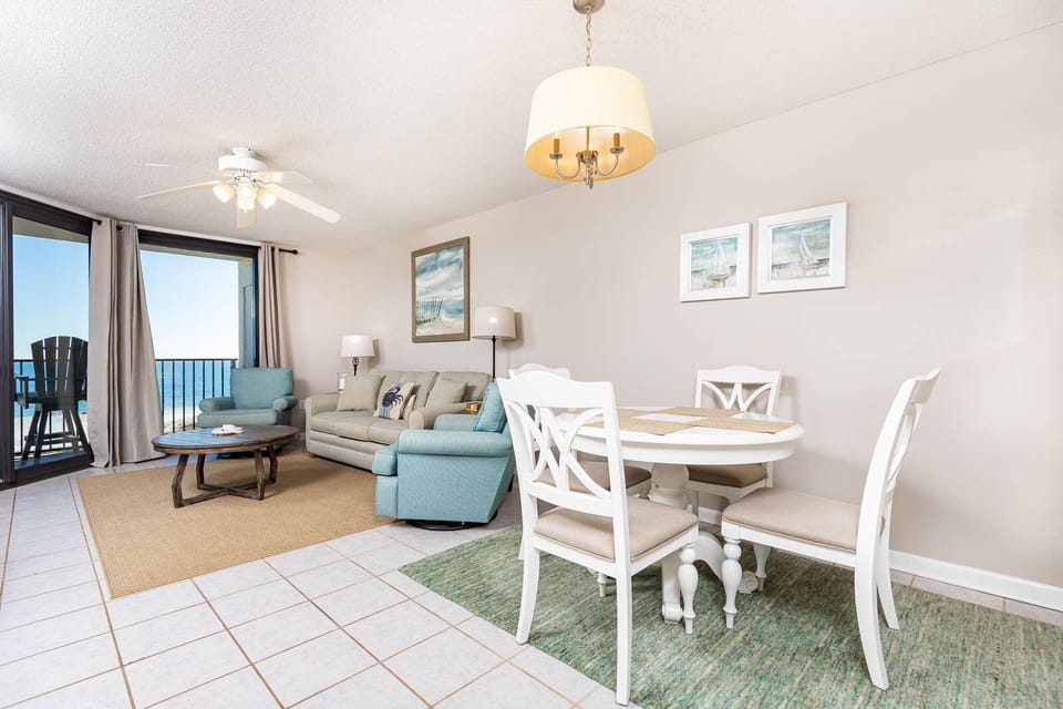 Cozy living area features a light sofa with queen sleeper, a round dining table, and a beautiful beachfront view