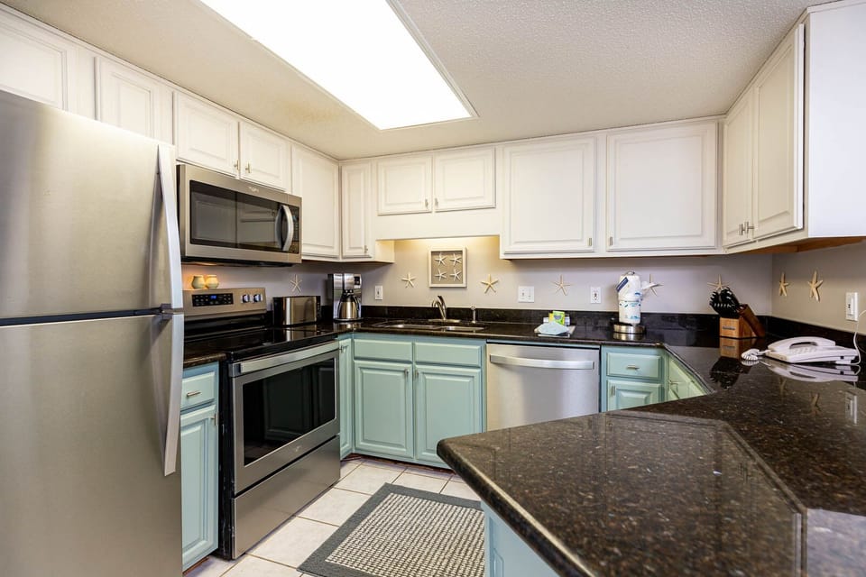The cabinetry complements the dark countertops in this kitchen, featuring a convenient breakfast bar and coffee station