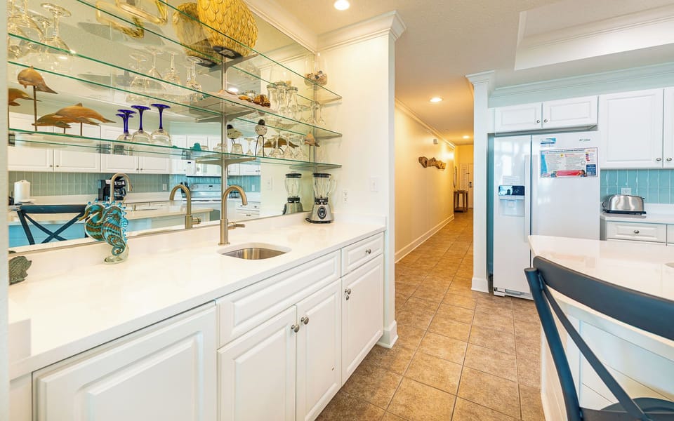 Soft tile underfoot leads you through the kitchen where glass shelves sparkle with coastal charm and sea life decor