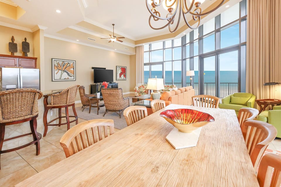 This inviting living area features a large TV, colorful decor, and stunning beachfront views through expansive windows