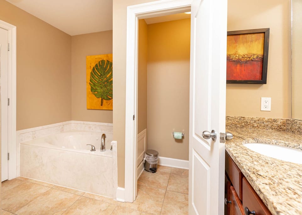 The master bath features a relaxing jetted tub, elegant granite countertops, and vibrant artwork for a refreshing atmosphere