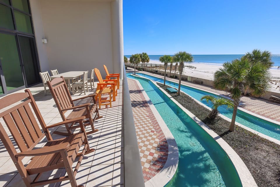 Enjoy the beachfront view from the balcony, featuring colorful seating and a serene lazy river ambiance