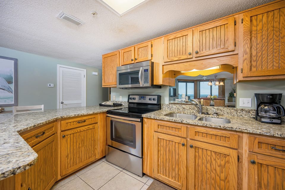 Prepare meals in the spacious kitchen featuring granite countertops, wooden cabinetry, and stainless appliances