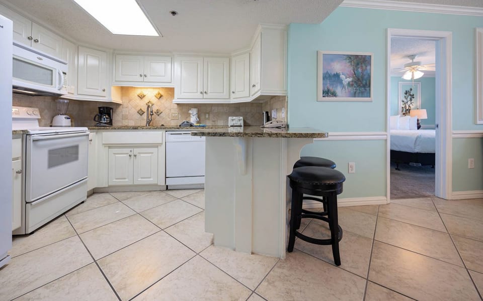 Prepare meals in this bright kitchen, featuring granite countertops, white appliances, and a breakfast bar