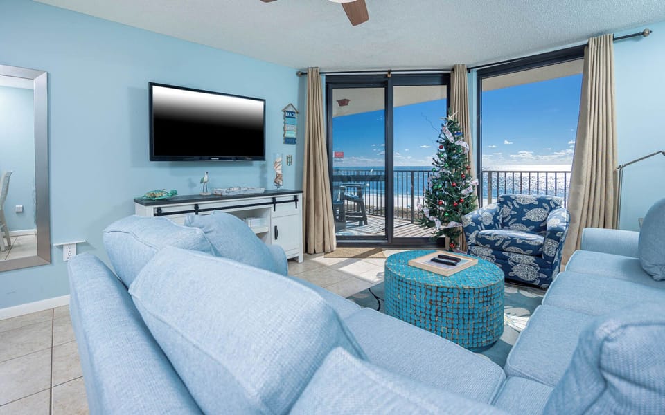 Cozy living area features a large blue sofa with queen sleeper, vibrant accent furniture, and balcony with a stunning view