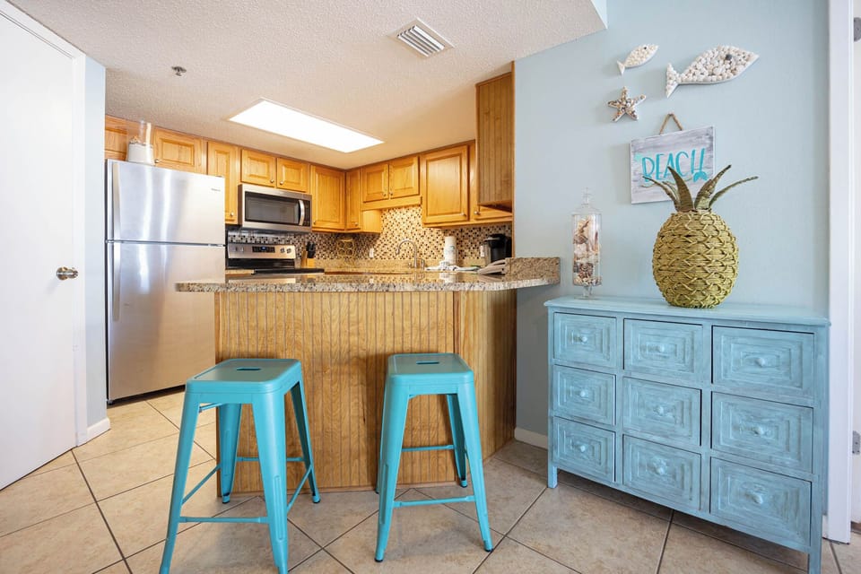 Turquoise bar stools complement the kitchen breakfast bar in this inviting kitchen area featuring granite countertops