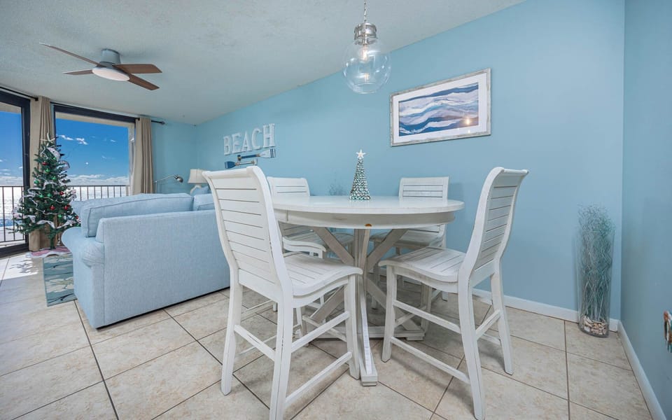 Bright blue walls complement a cozy dining area with a round table and white chairs, offering views of the gulf