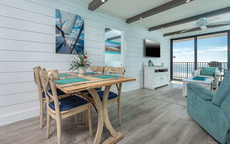 This inviting living area features a cozy seating arrangement, a TV, and a stunning beachfront view through large glass doors