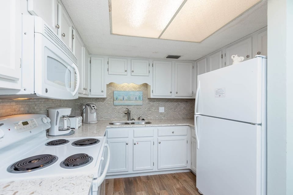 This kitchen features white cabinetry, stainless appliances, Keurig and coffee maker, perfect for preparing meals