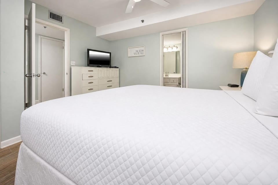 This cozy bedroom features a plush bed, a flat-screen TV, and an ensuite bathroom with a stylish vanity