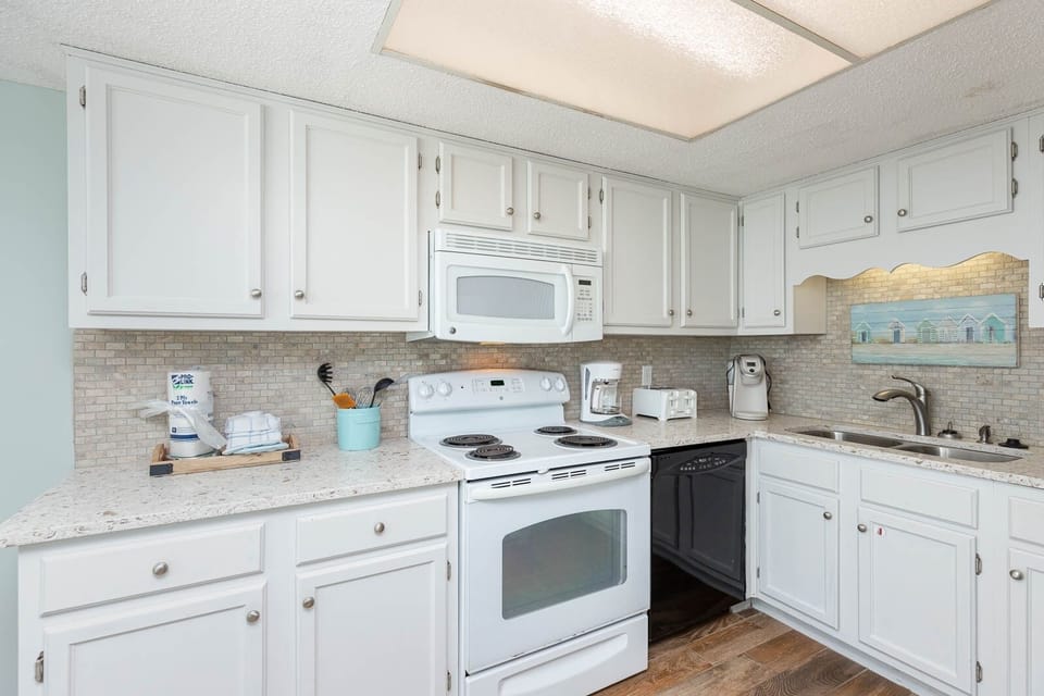 This kitchen features white cabinetry, a stylish backsplash, and stainless appliances, perfect for preparing meals