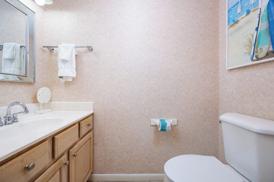 Light wood cabinetry complements the vanity in the half bath, featuring plush towels