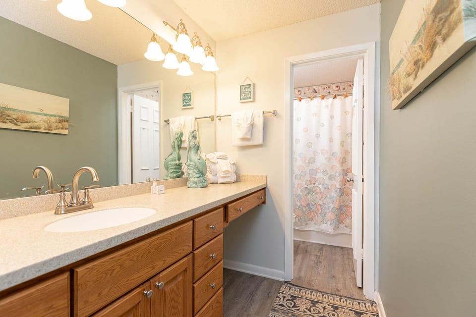 Refresh in this master bathroom featuring a spacious vanity, coastal decor, and a cheerful shower curtain