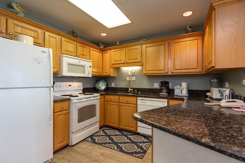 Prepare meals in this inviting kitchen featuring wooden cabinets, white appliances, and a cozy atmosphere