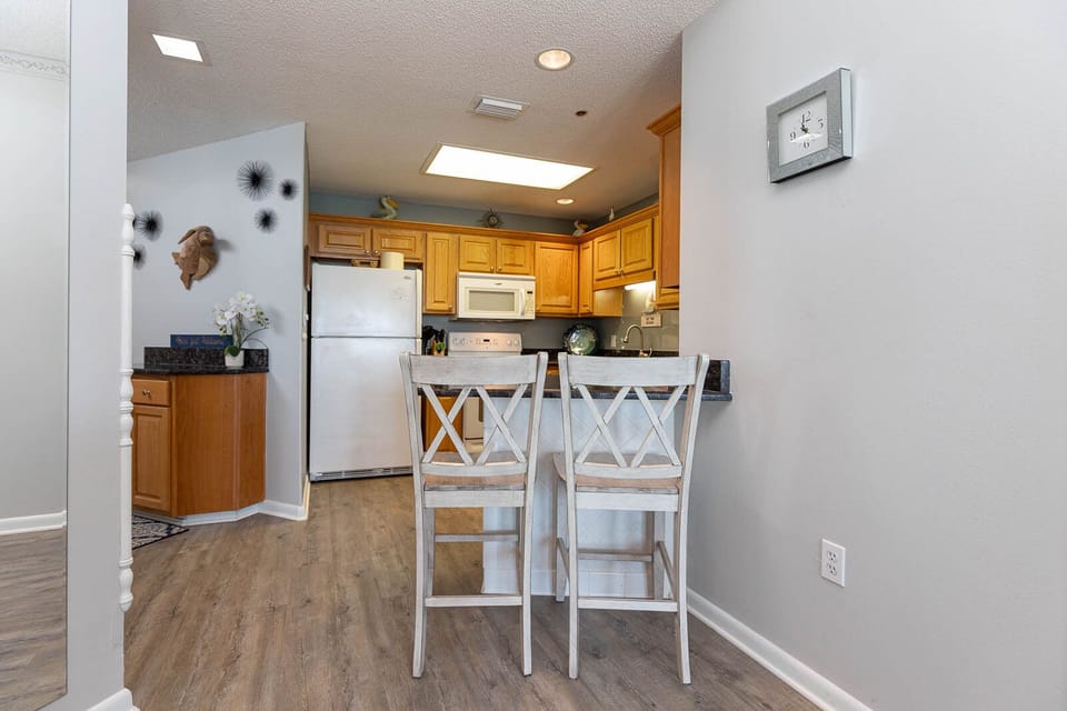 Gather around the breakfast bar with friends in this inviting kitchen featuring warm wooden cabinetry