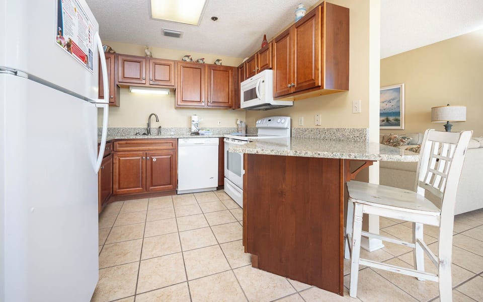 Prepare meals in the inviting kitchen featuring wooden cabinets, granite counters, and a convenient breakfast bar