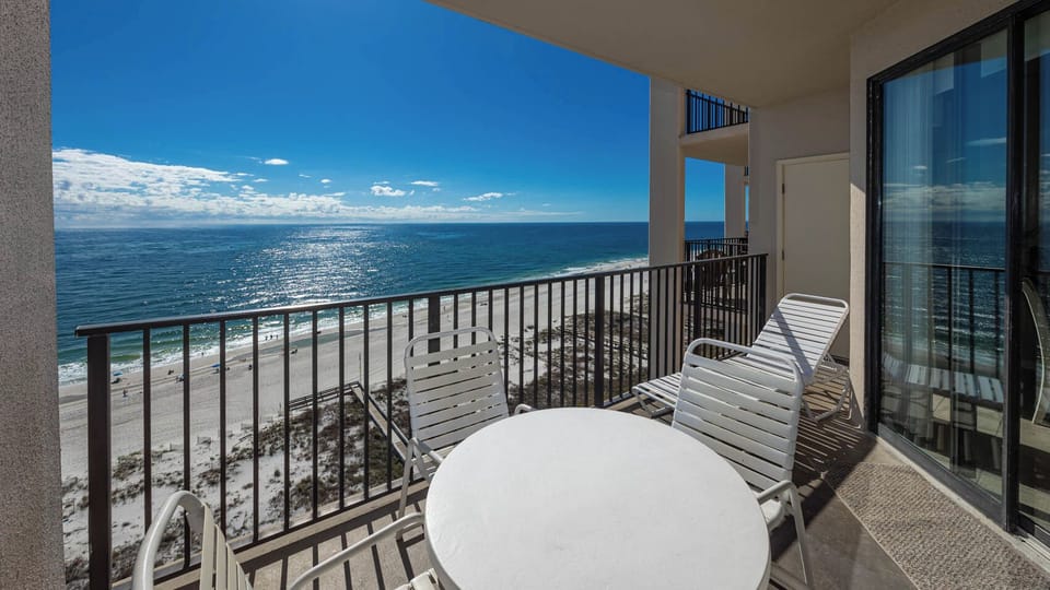 Relax on the balcony with a table and chairs, enjoying the beach with sparkling water and shoreline