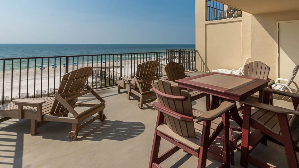 Relax on the spacious balcony with comfortable seating, enjoying panoramic views of the serene beach and sparkling waters