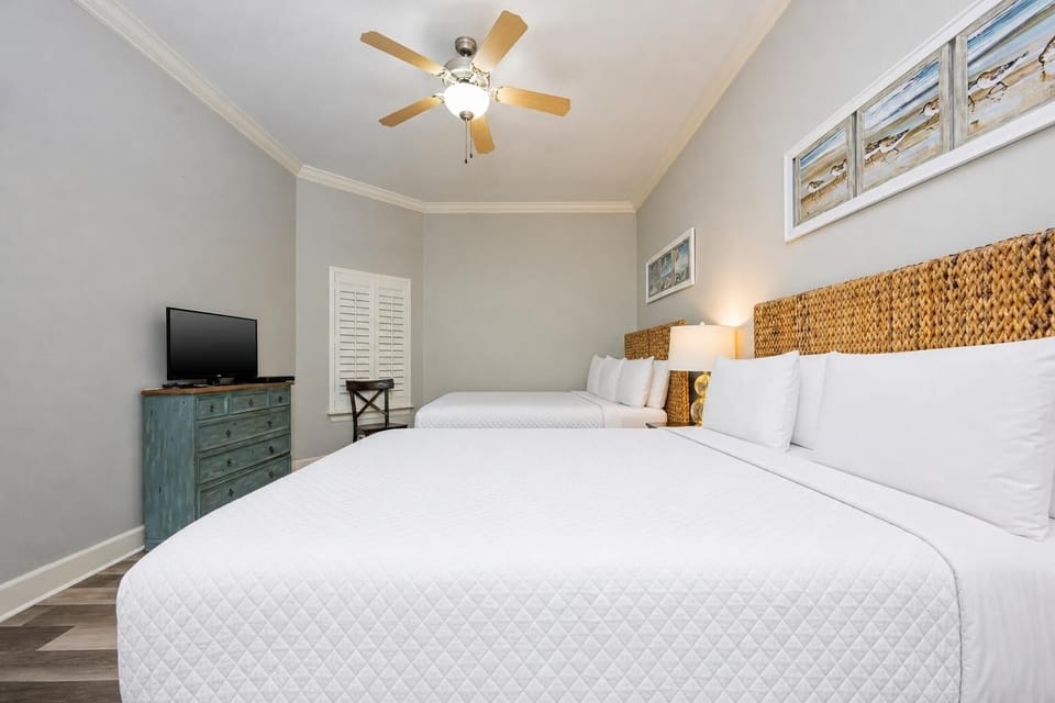 This guest bedroom features two comfortable queen beds, a TV, and coastal decor, perfect for a relaxing stay