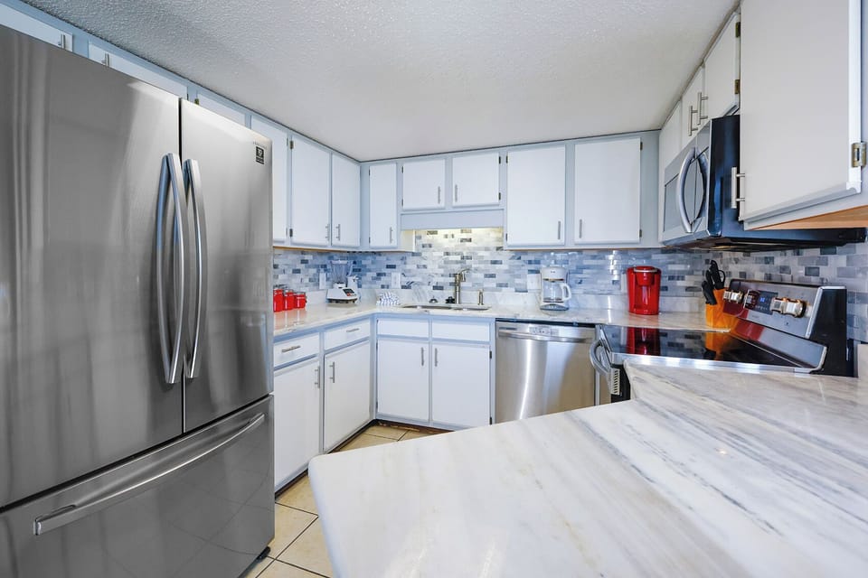 The modern kitchen features sleek cabinetry, a marbled countertop, and a stylish backsplash, perfect for culinary adventures