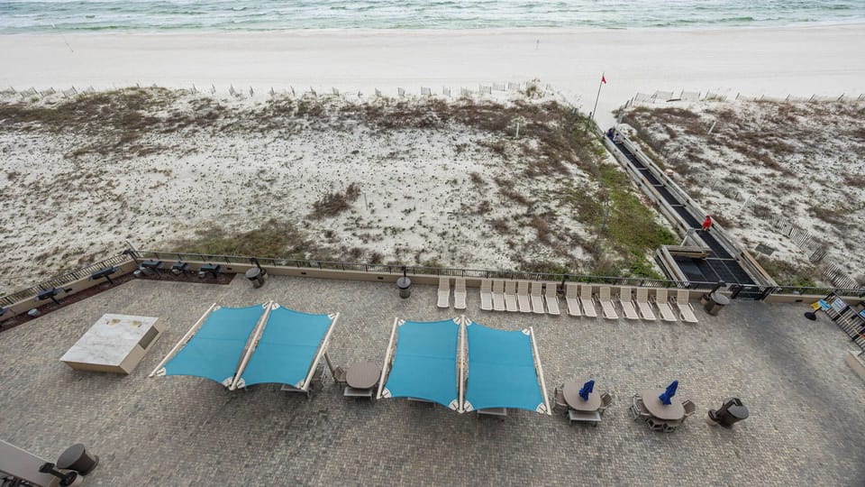 Relax under the shade of blue canopies on the spacious pool patio, just steps away from the beach
