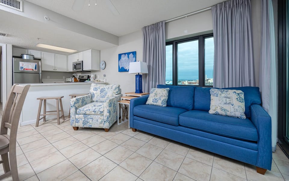 Relax on the comfortable blue sofa with queen sleeper while enjoying panoramic views through large windows