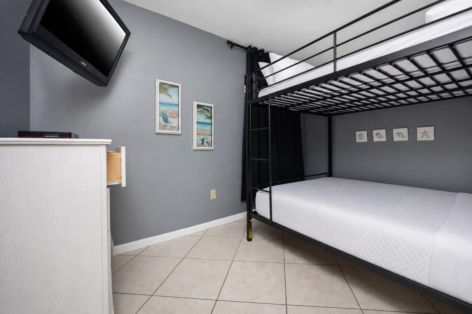 Guest bedroom featuring a cozy queen bunk bed, flat-screen TV, and beach-themed decor for a relaxing getaway