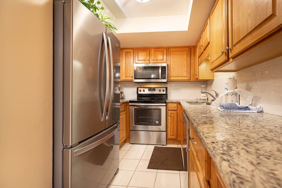 Modern kitchen with stainless appliances, warm wood cabinetry, and granite countertops, perfect for preparing meals