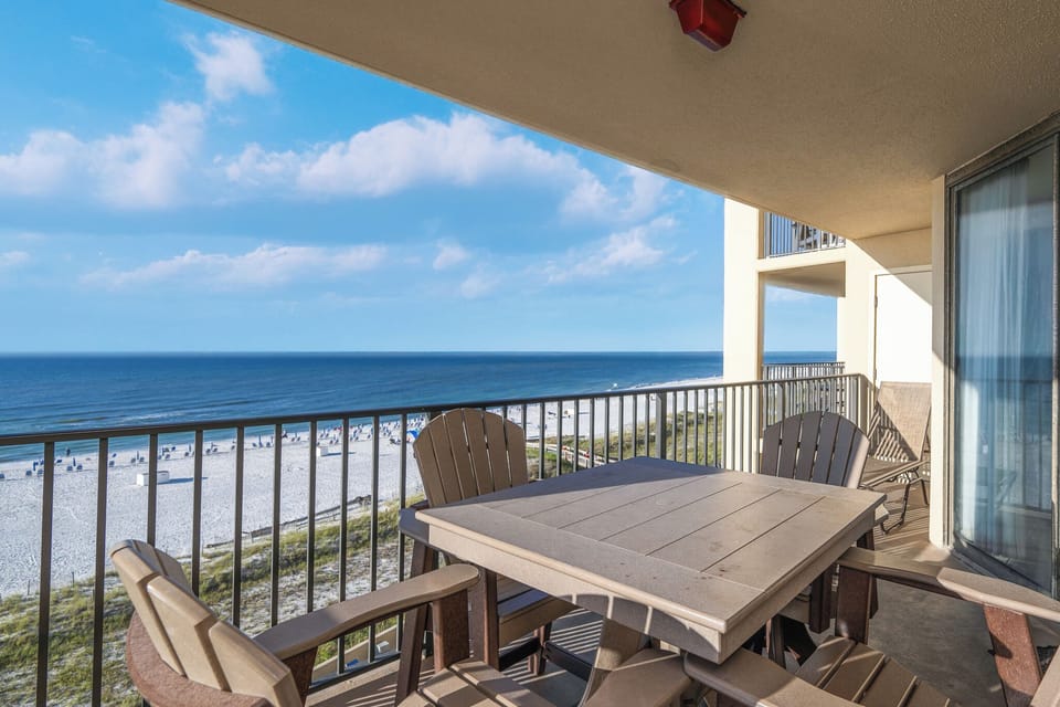 The spacious balcony features a dining table and chairs, offering a serene view of the beach and tranquil ocean waves