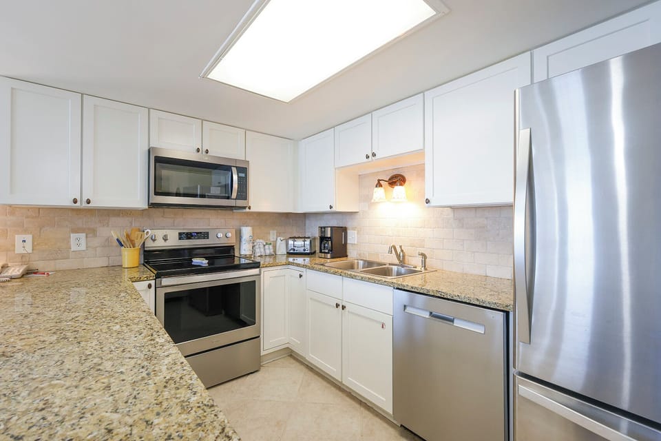 Bright modern kitchen features granite countertops, sleek stainless appliances, and ample cabinetry