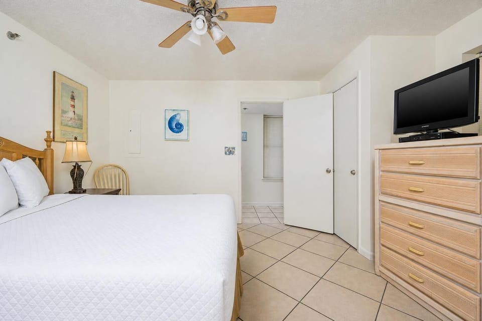 Cozy guest bedroom featuring a queen bed, ceiling fan, and beach decor for a relaxing retreat