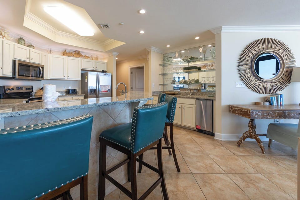 Inviting kitchen with granite countertops, stainless appliances, and stylish teal bar stools for casual dining