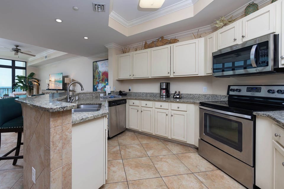 Modern kitchen featuring stainless appliances, granite countertops, and a view of the sparkling coastline