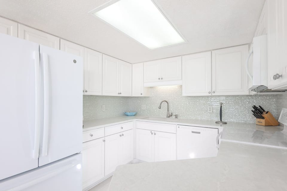 White cabinetry and sleek countertops complement the kitchen's design, featuring a convenient breakfast bar area