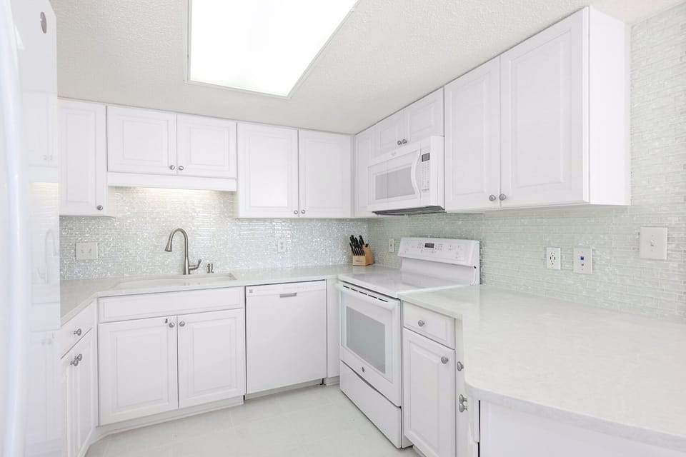 Bright white cabinetry and light countertops create a fresh, inviting space in this modern kitchen with ample storage