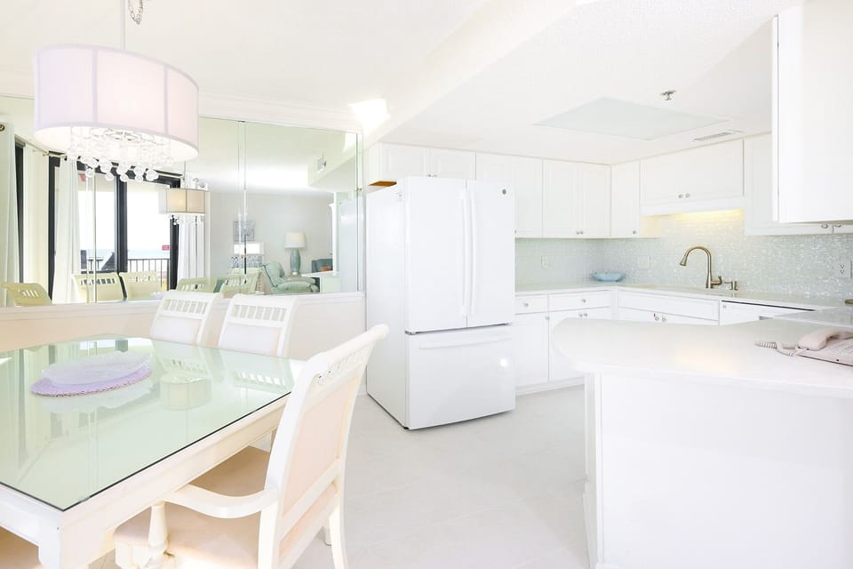 Bright kitchen area featuring white cabinetry, a dining table, and a view of the living room with a cozy seating arrangement