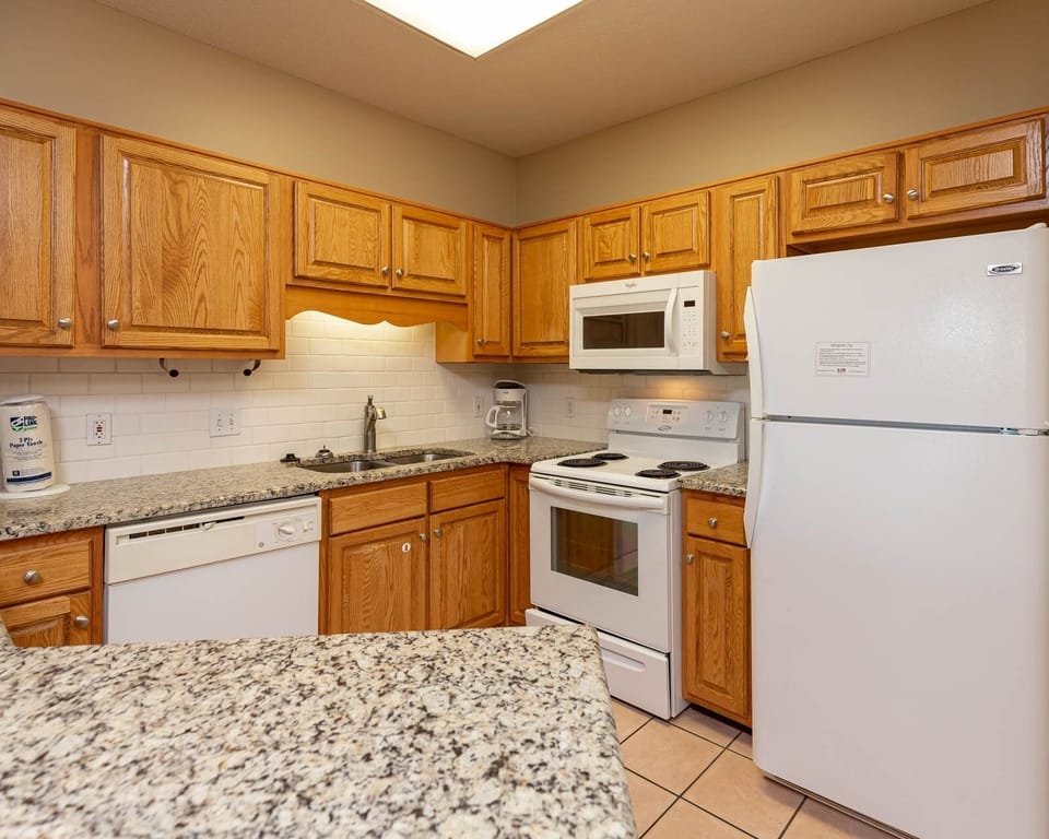 Relax in this inviting kitchen with a stylish subway tile backsplash, white appliances, and warm wood cabinetry