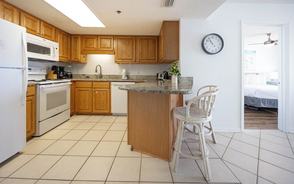 Bright kitchen featuring wooden cabinetry, a granite countertop, and a breakfast bar with seating, leading to the master