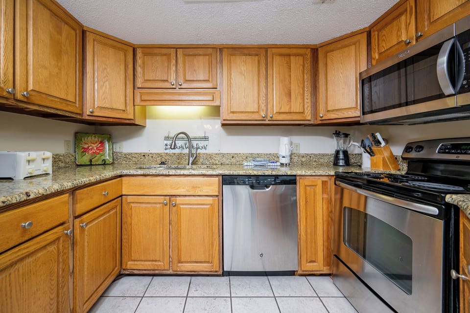 Kitchen featuring warm wooden cabinetry, granite countertops, and stainless appliances, creating a functional cooking space
