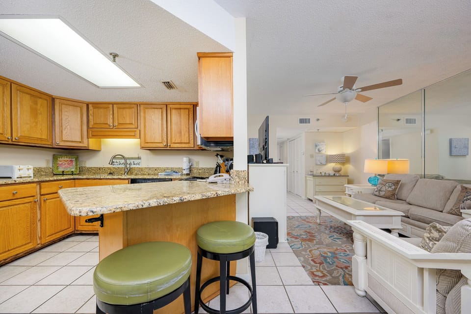Kitchen featuring wood cabinetry, a granite countertop, and a cozy bar area with green stools