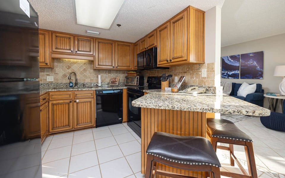 Experience cooking in this inviting kitchen with rich wood cabinetry, granite countertops, and black appliances