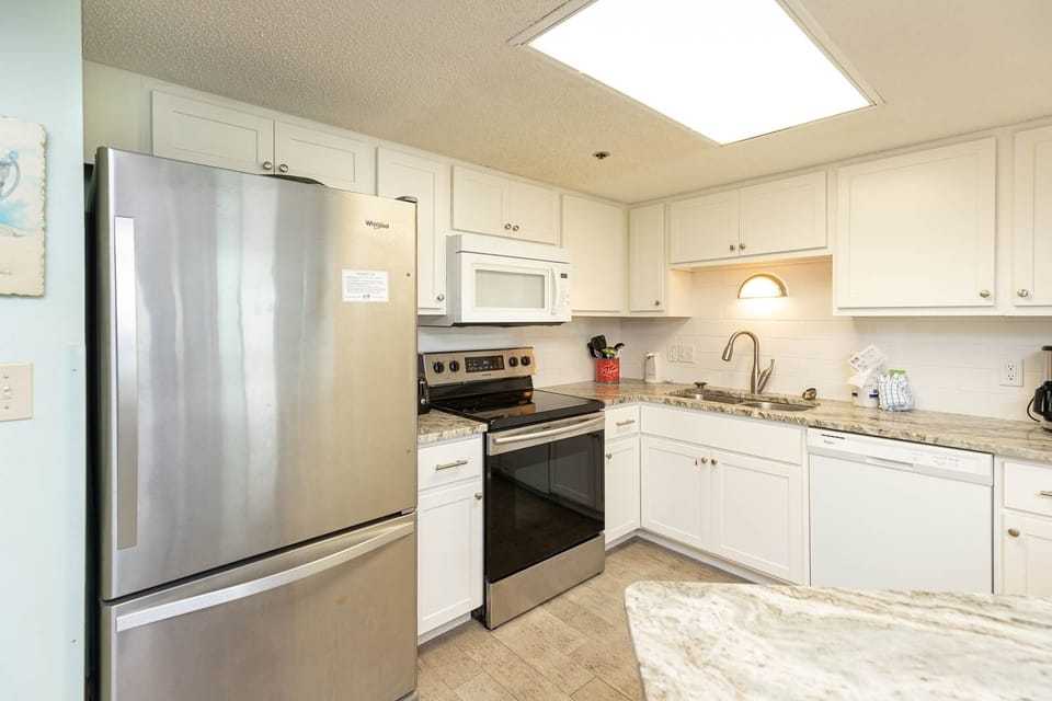 Prepare meals in this bright kitchen featuring white and stainless appliances and stylish cabinetry