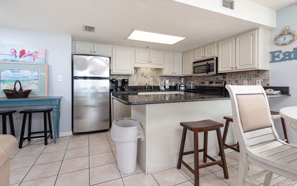 Kitchen area features a sleek granite countertop, stainless appliances, and a cozy breakfast bar with seating
