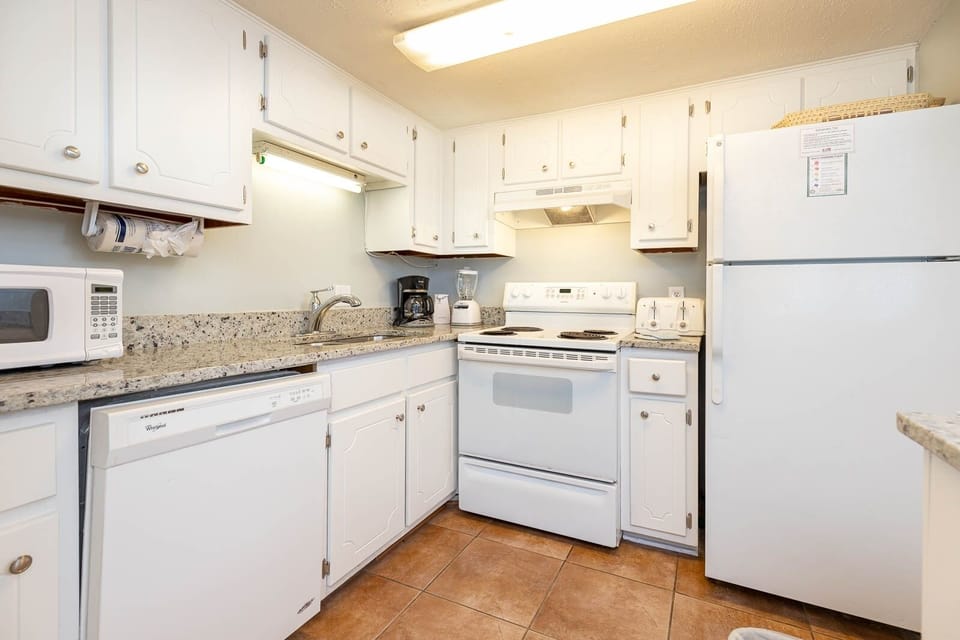 This kitchen features white cabinetry, granite countertops, and essential appliances for a convenient cooking experience