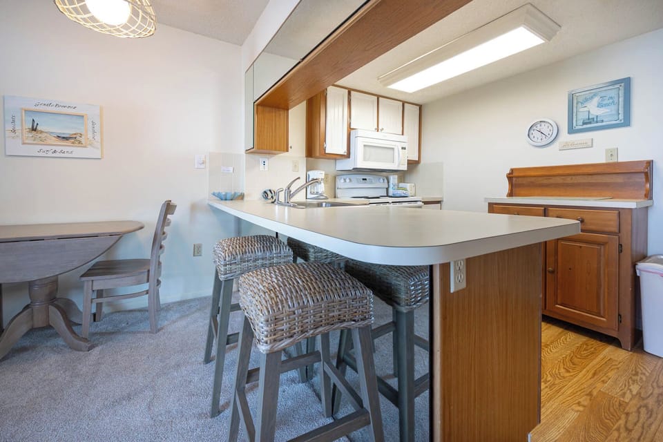 The kitchen features a spacious countertop, stylish bar stools, and welcoming beach decor for a delightful cooking experience