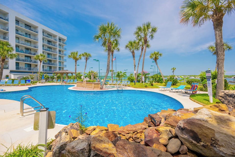 Take a refreshing dip in the pool surrounded by palm trees and lounge chairs, perfect for unwinding after a day at the beach