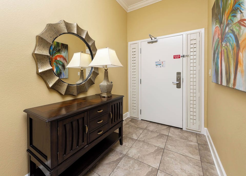 Inviting entryway featuring a stylish mirror, decorative lamp, and colorful artwork for a warm welcome
