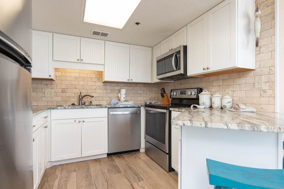 Prepare meals in this inviting kitchen with stylish cabinetry, stainless appliances, and a charming coastal decor